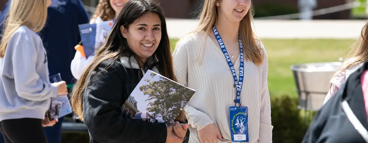 Students standing outside, holding informational brochures